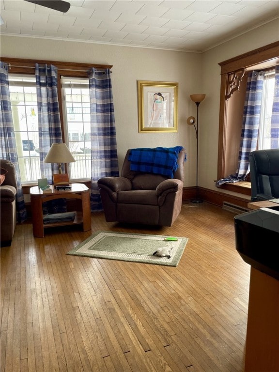 living area featuring hardwood / wood-style flooring, baseboards, and ornamental molding