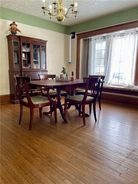 dining area with hardwood / wood-style floors, a notable chandelier, baseboards, and a textured ceiling
