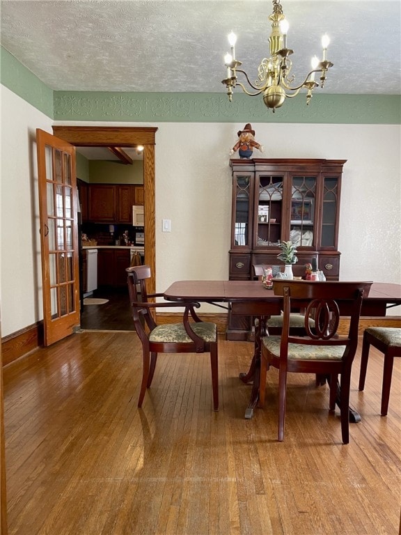 405 2nd Ave, Wayland, NY 14572 - dining room with wood finished floors, a chandelier, a textured ceiling, and baseboards