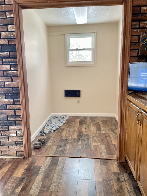 laundry room featuring baseboards, dark wood-style flooring, and a textured ceiling