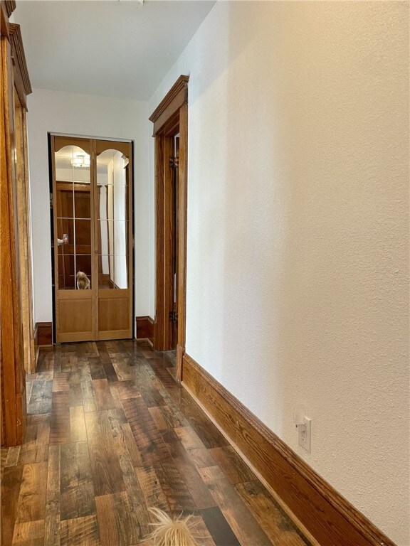 hall with dark wood-type flooring and baseboards