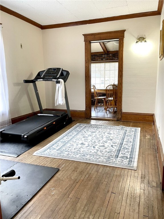 workout area with baseboards, hardwood / wood-style floors, and crown molding