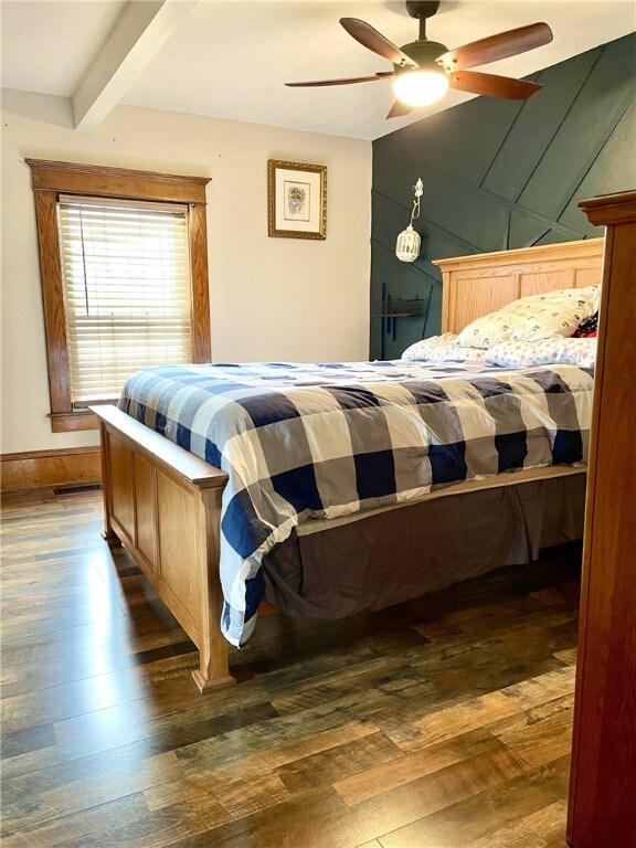 bedroom with ceiling fan, beamed ceiling, visible vents, and hardwood / wood-style floors
