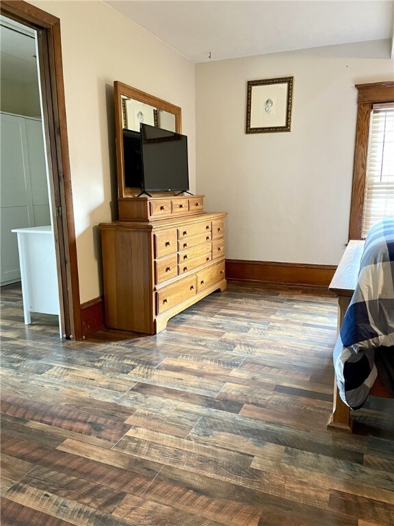 bedroom with baseboards and dark wood-style flooring