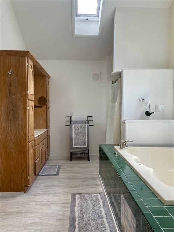 405 2nd Ave, Wayland, NY 14572 - bathroom featuring tiled bath, a shower with shower curtain, vanity, and baseboards