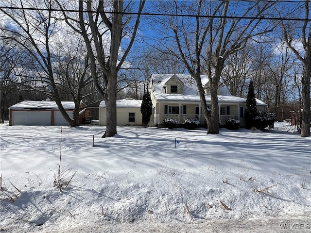 new england style home featuring an outbuilding, a garage, and covered porch