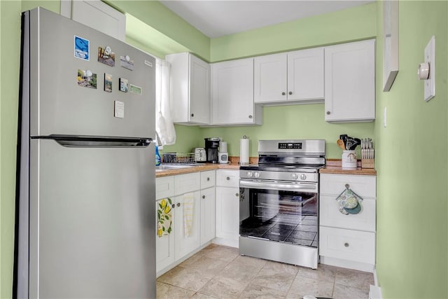 kitchen featuring appliances with stainless steel finishes, white cabinets, and wood counters