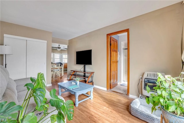 living room featuring heating unit, light hardwood / wood-style flooring, and ceiling fan