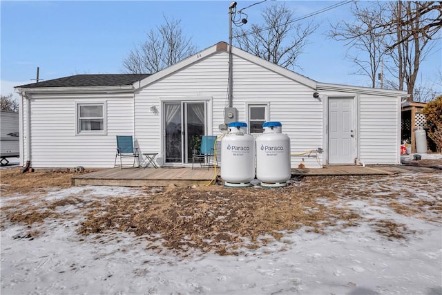 snow covered back of property with a wooden deck