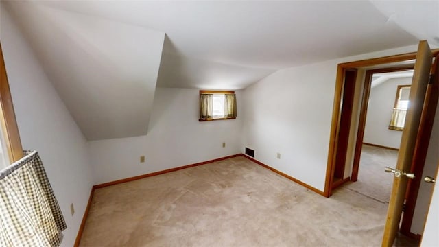 bonus room with lofted ceiling and light colored carpet