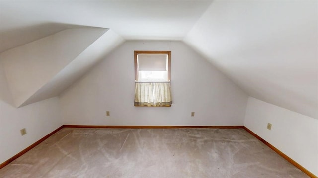 bonus room with vaulted ceiling and light carpet