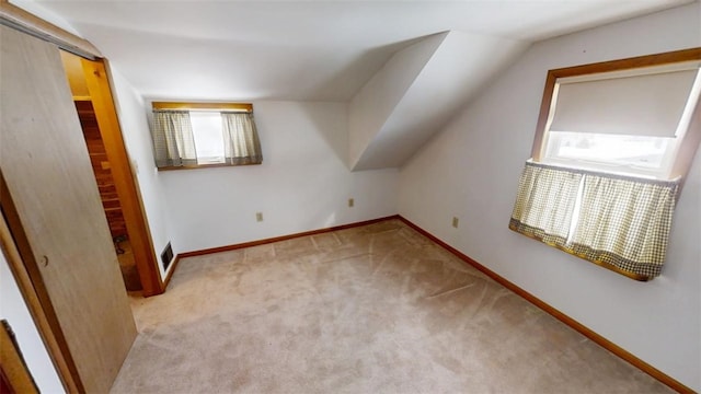 bonus room with vaulted ceiling and light colored carpet