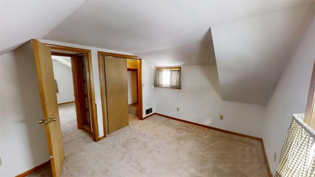 bonus room with lofted ceiling and light carpet