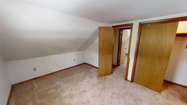 additional living space featuring vaulted ceiling and light colored carpet