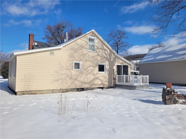 snow covered back of property featuring a deck