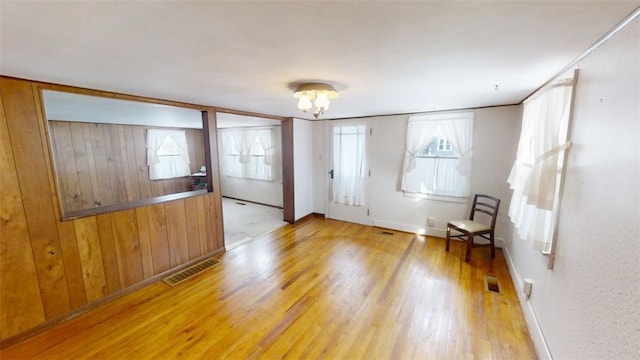 entryway with an inviting chandelier, hardwood / wood-style flooring, and wooden walls