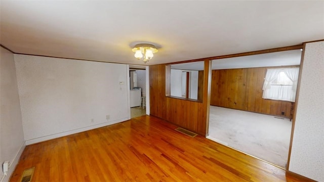 empty room with wooden walls and hardwood / wood-style floors