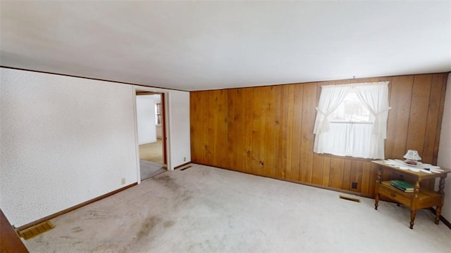 carpeted spare room featuring wooden walls