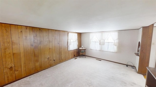 empty room with light carpet and wood walls