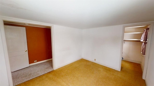 unfurnished bedroom with light carpet, a spacious closet, and a closet