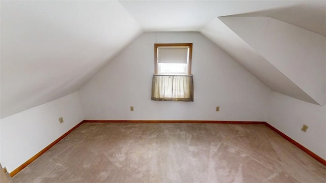 additional living space featuring vaulted ceiling and light carpet