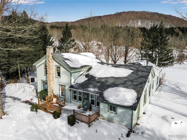 snow covered back of property featuring a deck with mountain view