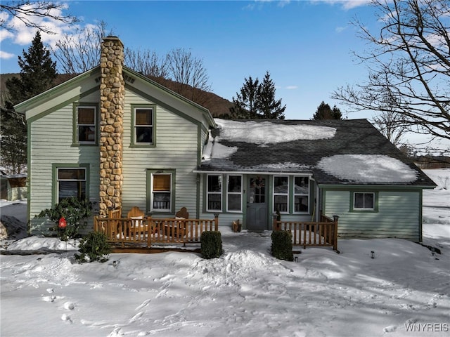 snow covered back of property with a deck