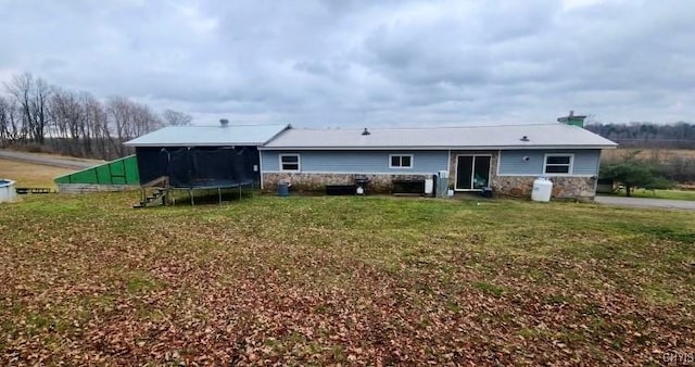 back of house with a yard and a trampoline