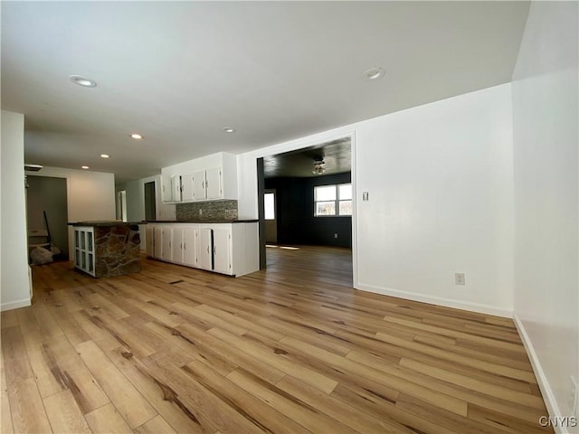 kitchen featuring white cabinetry, kitchen peninsula, tasteful backsplash, and light hardwood / wood-style flooring