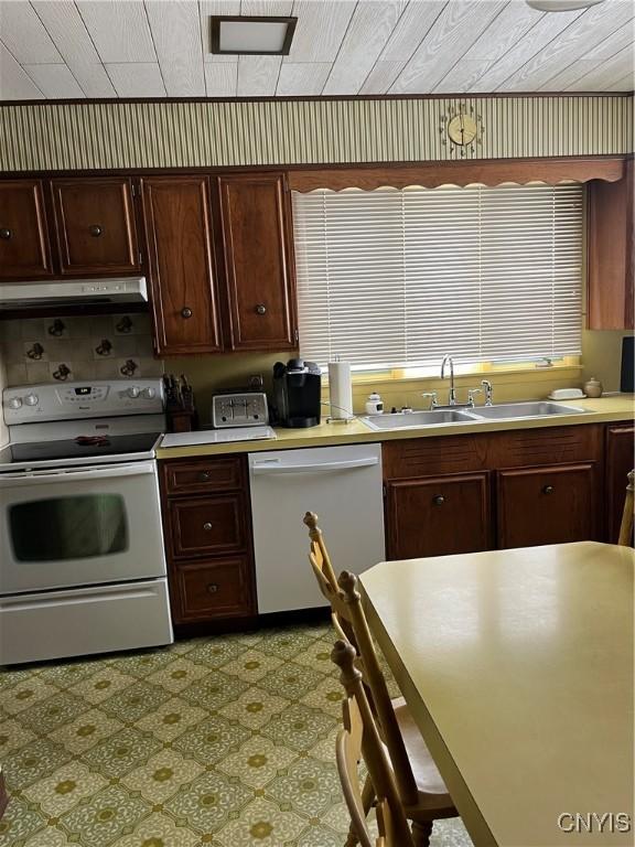 kitchen with dark brown cabinets, sink, and white appliances