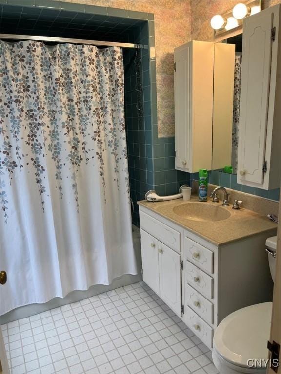 full bathroom with tile walls, vanity, tile patterned floors, toilet, and shower / bath combo with shower curtain