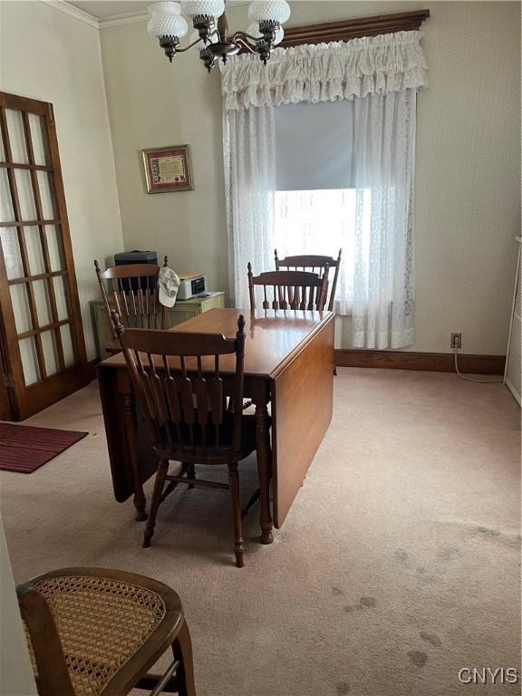 carpeted dining space with ornamental molding and a notable chandelier