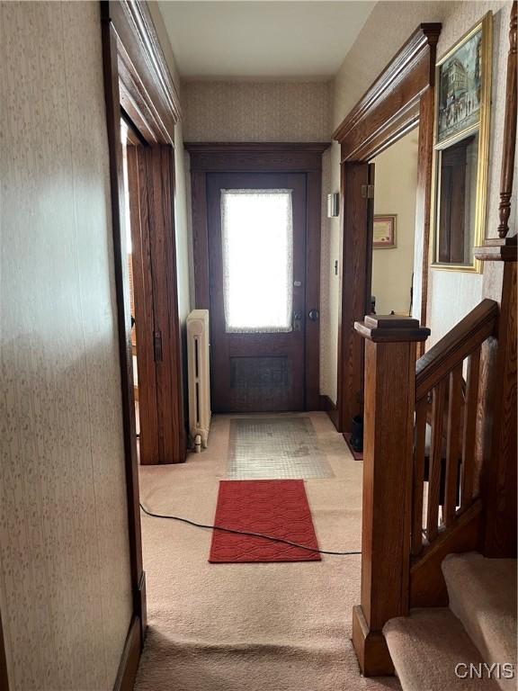 doorway with light colored carpet and radiator heating unit