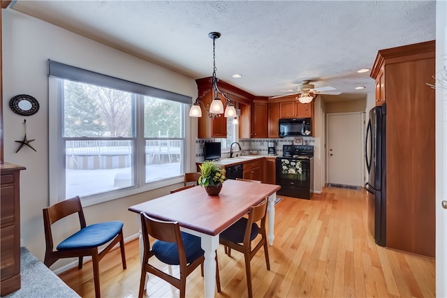 kitchen featuring hanging light fixtures, light hardwood / wood-style flooring, black appliances, and sink