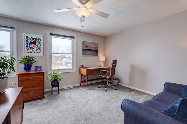 office space with ceiling fan, a healthy amount of sunlight, light colored carpet, and a textured ceiling