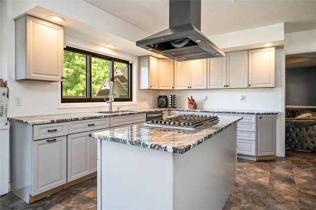 kitchen with sink, island range hood, light stone countertops, white cabinets, and a kitchen island