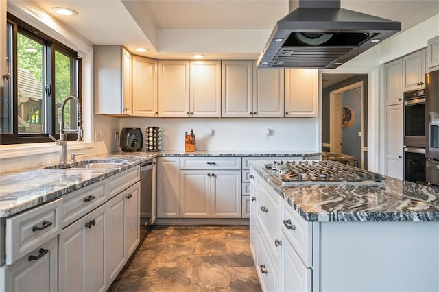 kitchen with sink, island range hood, stainless steel appliances, light stone countertops, and white cabinets