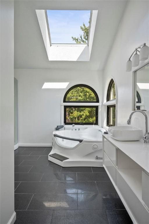 bathroom with vanity, lofted ceiling with skylight, and a tub