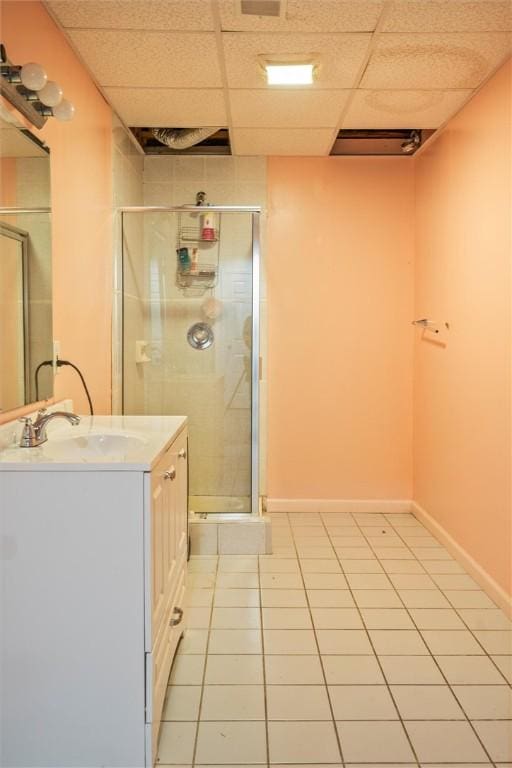 bathroom featuring tile patterned floors, vanity, a shower with shower door, and a paneled ceiling