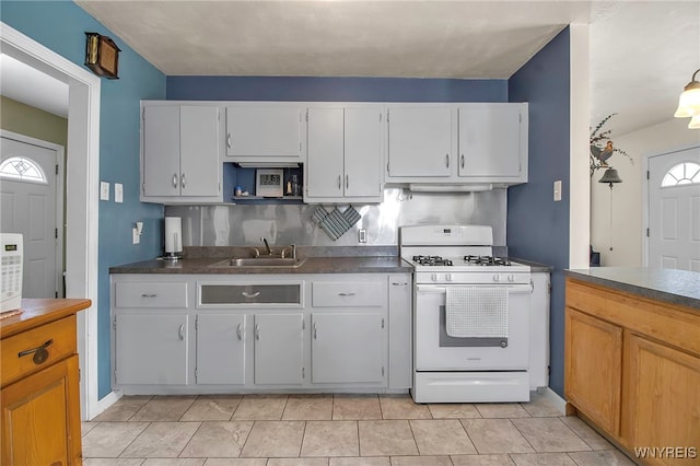 kitchen with white cabinets, light tile patterned floors, sink, and white range with gas stovetop