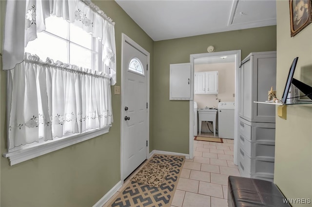 foyer with washer / clothes dryer, sink, and light tile patterned floors