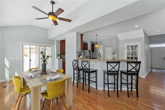 dining area featuring lofted ceiling, a healthy amount of sunlight, and light wood-type flooring