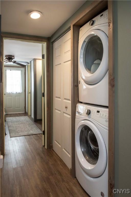 washroom with dark wood-type flooring, ceiling fan, and stacked washer / drying machine