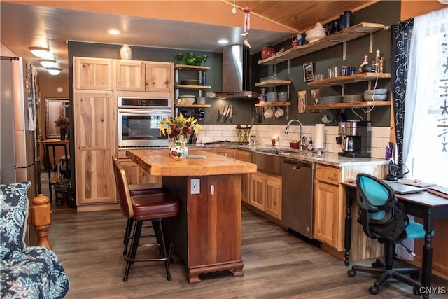 kitchen featuring wall chimney range hood, dark wood-type flooring, appliances with stainless steel finishes, butcher block counters, and a center island