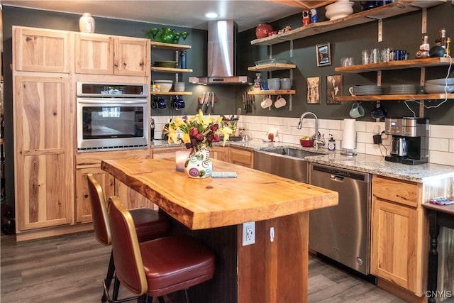 kitchen featuring wall chimney exhaust hood, sink, butcher block countertops, stainless steel appliances, and backsplash