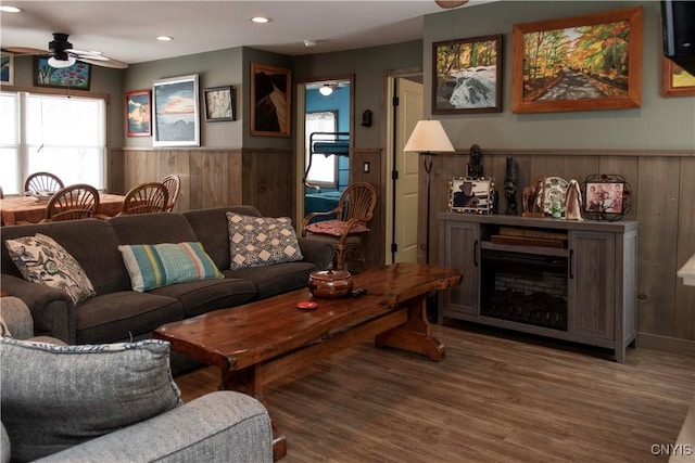 living room with hardwood / wood-style floors, a fireplace, ceiling fan, and wood walls