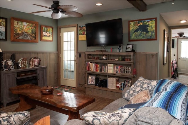 sitting room featuring ceiling fan, wood-type flooring, beam ceiling, and a fireplace