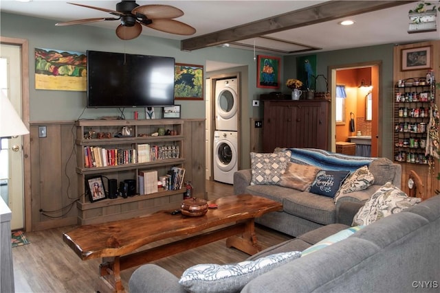 living room with hardwood / wood-style flooring, stacked washer and dryer, ceiling fan, and beamed ceiling