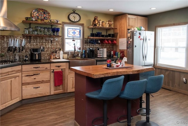 kitchen featuring wall chimney range hood, sink, appliances with stainless steel finishes, butcher block counters, and dark hardwood / wood-style flooring