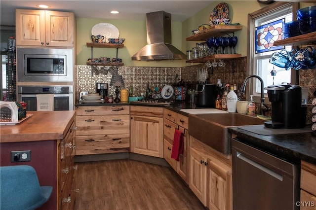 kitchen featuring wall chimney exhaust hood, sink, tasteful backsplash, appliances with stainless steel finishes, and dark hardwood / wood-style floors